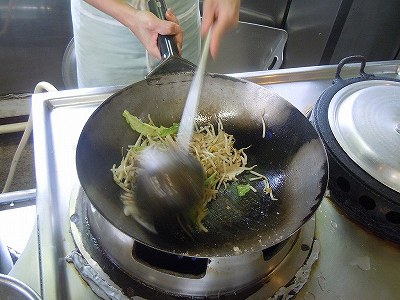 野菜を炒める店主